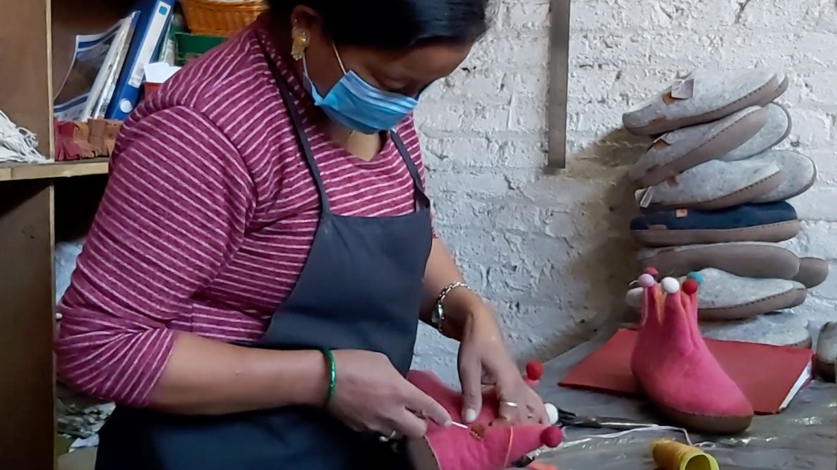 A Betterfelt artisan adding their signatire stitch to a finished pair of Betterfelt slippers